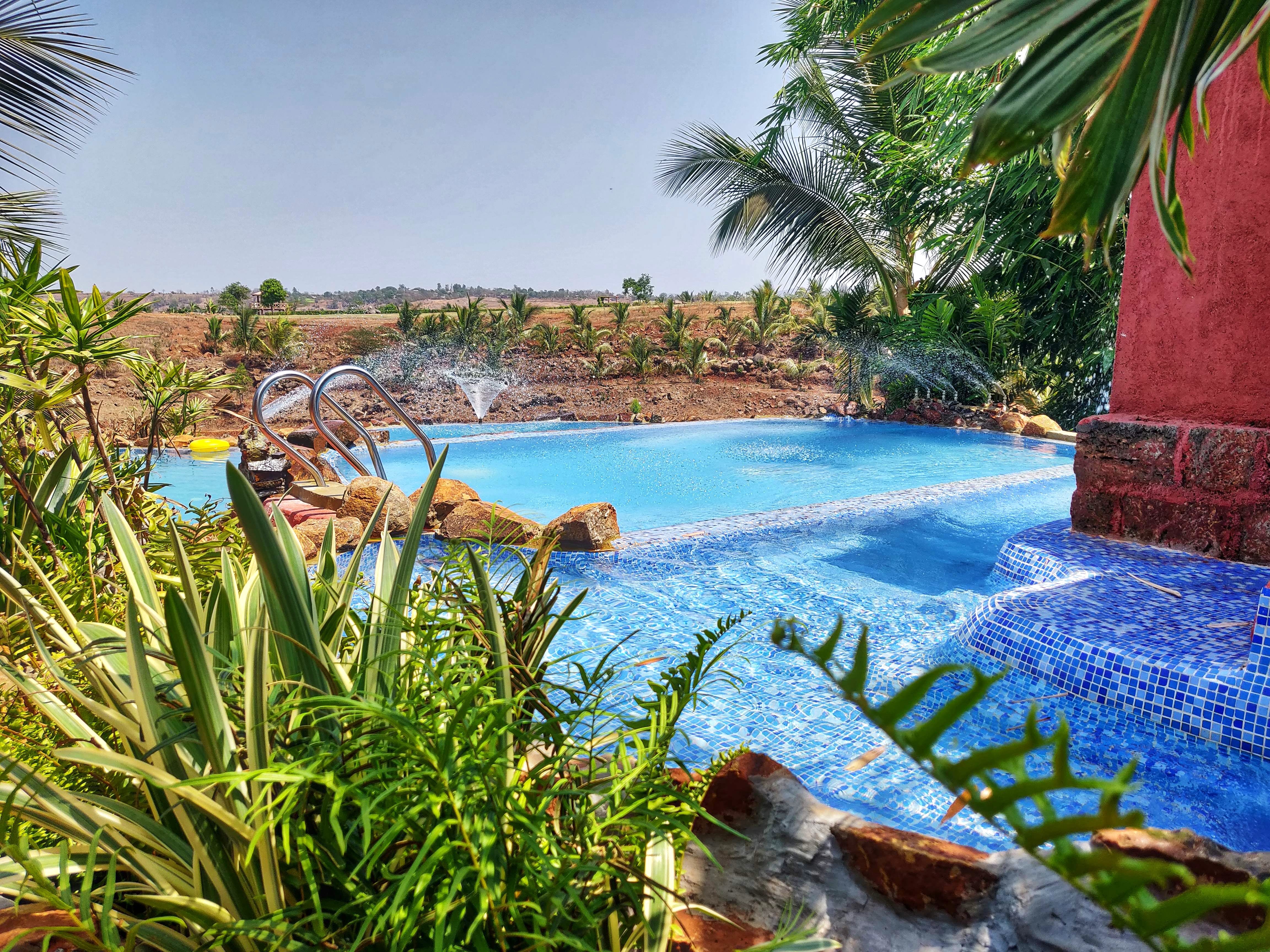 Swimming pool,Natural landscape,Vegetation,Majorelle blue,Azure,Resort,Property,Palm tree,Vacation,Water