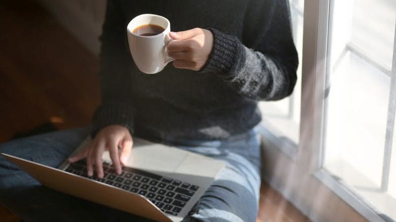 Computer keyboard,Laptop,Cup,Hand,Floor,Technology,Electronic device,Coffee cup,Sitting,Netbook