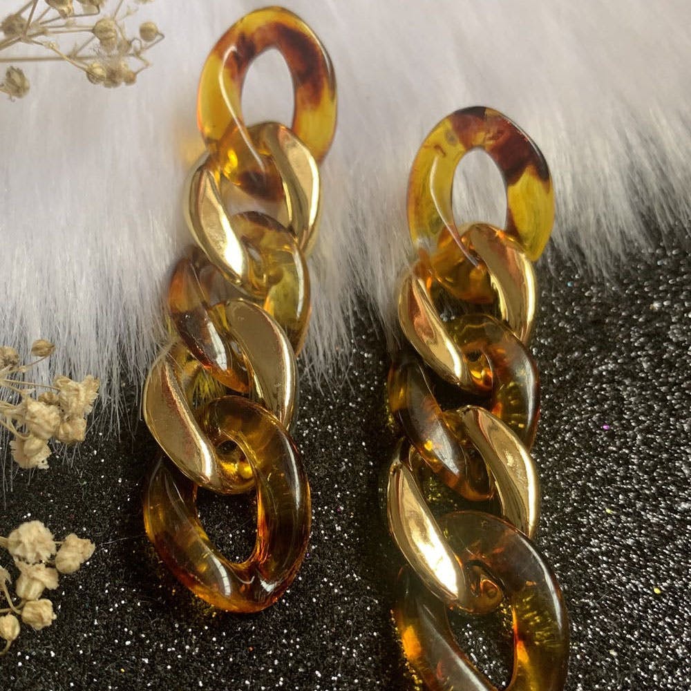 Gold,Body jewelry,Amber,Jewellery,Font,Art,Metal,Cod liver oil,Glass,Fashion accessory