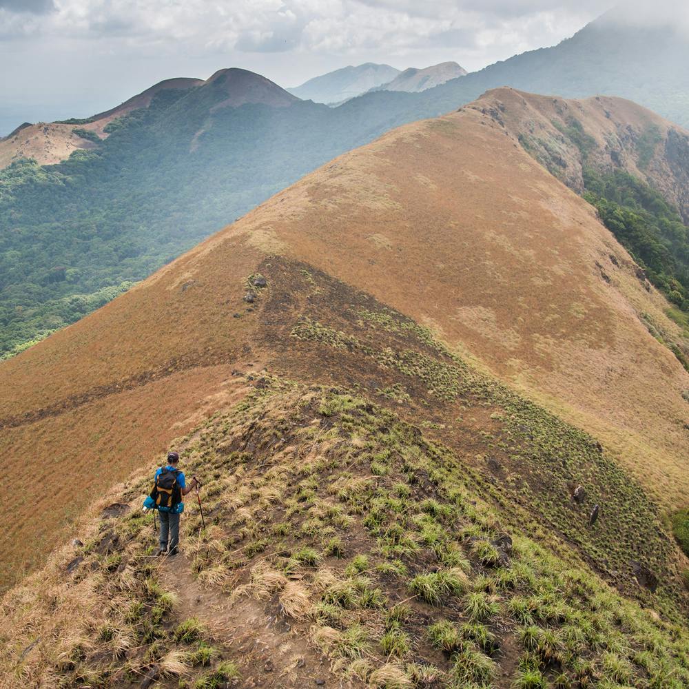 Sky,Cloud,Mountain,Plant community,Plant,Slope,People in nature,Terrain,Grass,Landscape